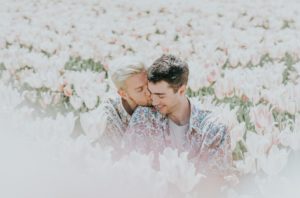 two man sitting on pink flower field on a date after a therapy session 