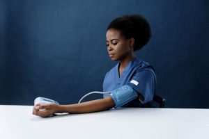 a healthcare worker measuring her own blood pressure to show the physical effects of anxiety 